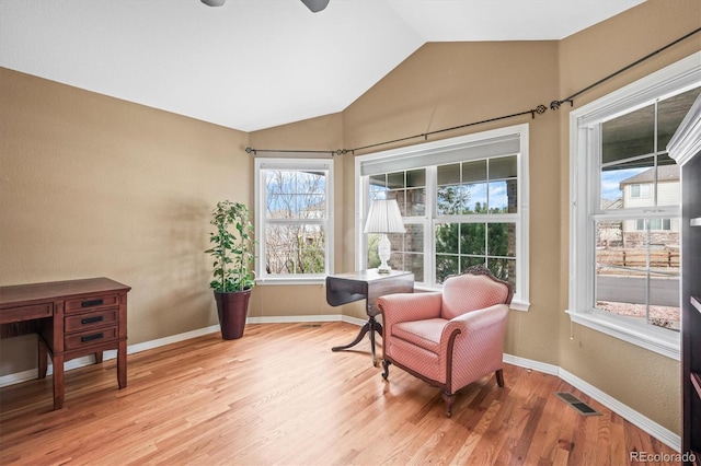 living area featuring vaulted ceiling, baseboards, visible vents, and light wood-style floors