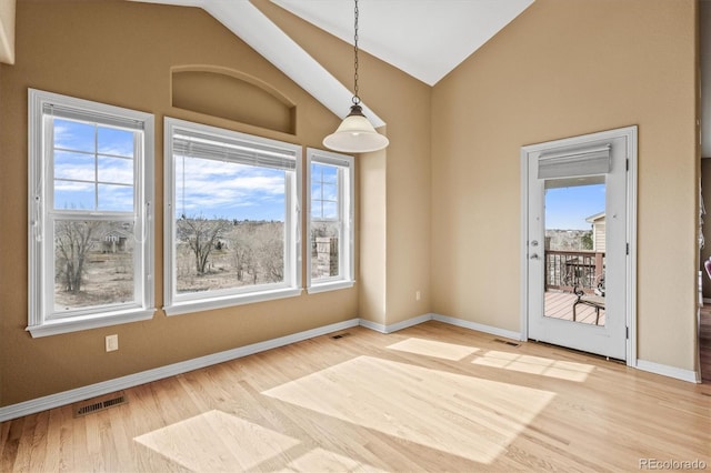 unfurnished dining area featuring lofted ceiling, visible vents, and plenty of natural light