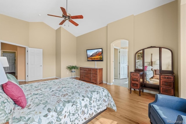 bedroom with arched walkways, ceiling fan, wood finished floors, high vaulted ceiling, and baseboards