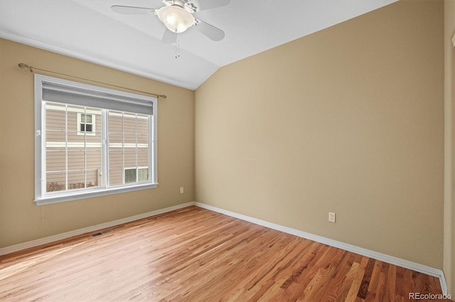 empty room with baseboards, visible vents, a ceiling fan, vaulted ceiling, and light wood-style floors