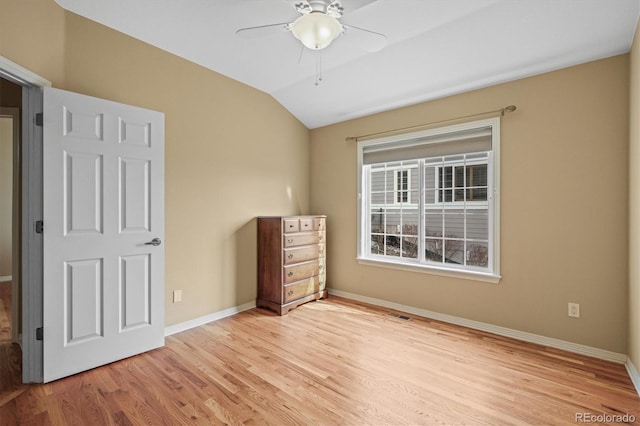 unfurnished bedroom featuring light wood-style floors, vaulted ceiling, baseboards, and a ceiling fan