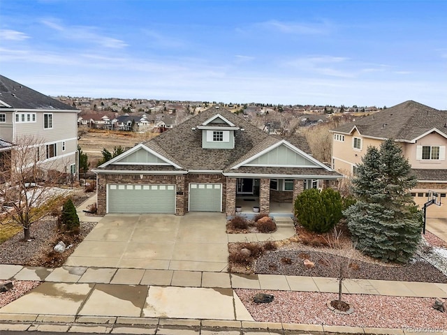 craftsman-style home with a shingled roof, concrete driveway, an attached garage, covered porch, and brick siding