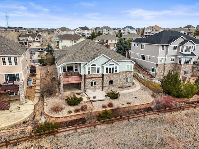 rear view of property with stone siding, a residential view, central AC unit, and a patio