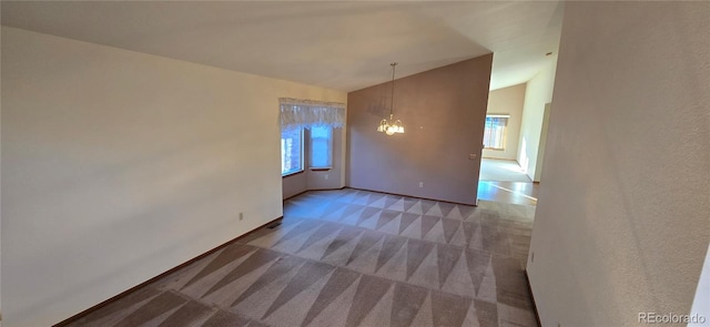 spare room with carpet, lofted ceiling, and a notable chandelier