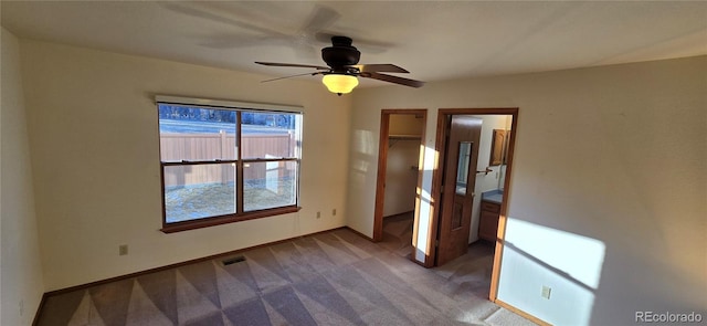 unfurnished bedroom with carpet flooring, ceiling fan, a walk in closet, and a closet