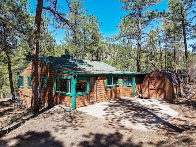 5235 Cheyenne Rd, Indian Hills, CO 80454 - chalet / cabin with a storage shed, a chimney, and a view of trees