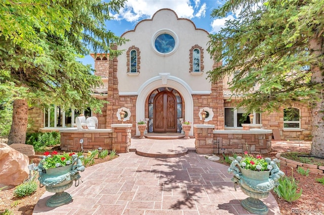 view of front of home featuring stone siding and stucco siding