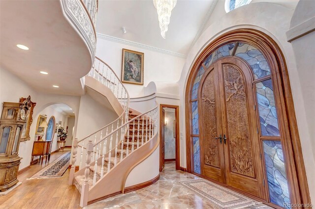 entrance foyer featuring hardwood / wood-style flooring, a notable chandelier, and crown molding