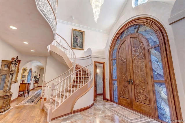 entryway with arched walkways, a high ceiling, stairs, and baseboards