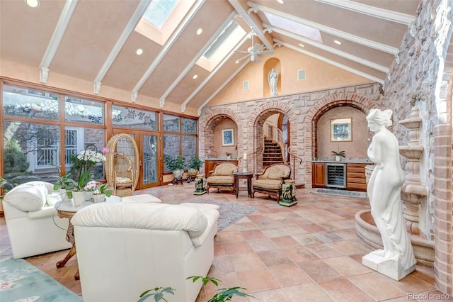 living room with a skylight, tile patterned flooring, wine cooler, ceiling fan, and high vaulted ceiling