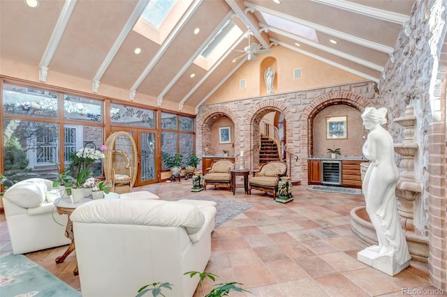 sunroom / solarium with ceiling fan, arched walkways, beverage cooler, visible vents, and lofted ceiling with skylight