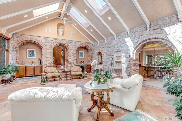 tiled living room featuring high vaulted ceiling, sink, ceiling fan, and a skylight