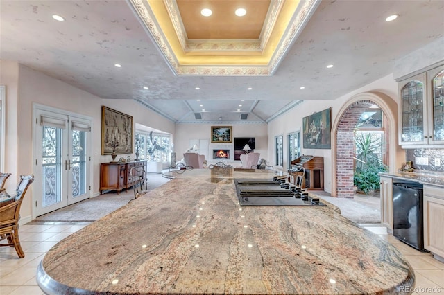 kitchen with light tile patterned flooring, black dishwasher, french doors, light stone counters, and lofted ceiling