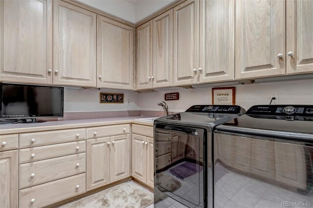 laundry area featuring light tile patterned flooring, sink, washing machine and dryer, and cabinets