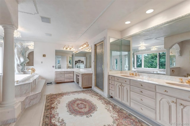 bathroom featuring ornate columns, vanity, a bath, and a stall shower