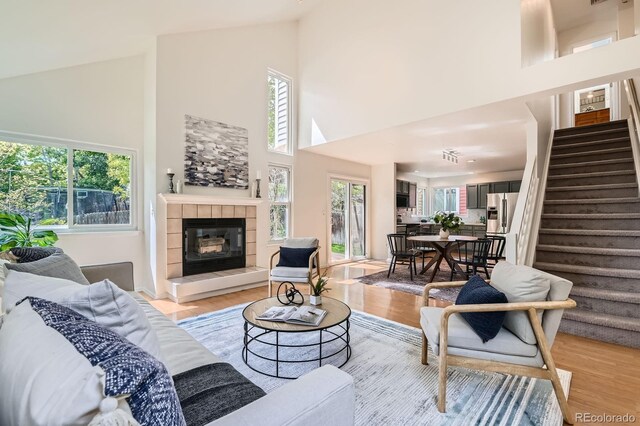 744 Owl Dr, Louisville, CO 80027 - living area with stairway, high vaulted ceiling, light wood-type flooring, and a tiled fireplace