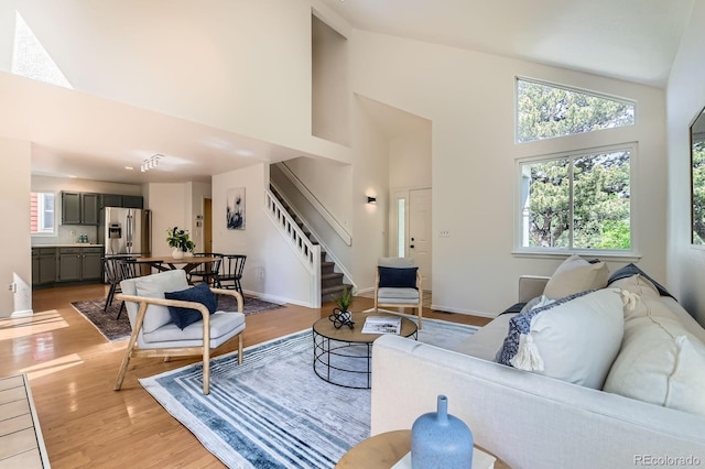744 Owl Dr, Louisville, CO 80027 - living area featuring stairway, high vaulted ceiling, healthy amount of natural light, and light wood-style flooring
