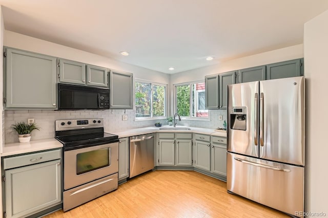 744 Owl Dr, Louisville, CO 80027 - kitchen with appliances with stainless steel finishes, a sink, light countertops, tasteful backsplash, and light wood-style floors