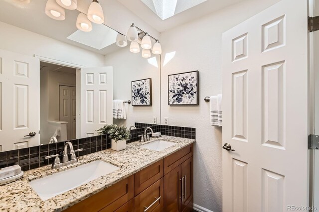 744 Owl Dr, Louisville, CO 80027 - bathroom with a skylight, double vanity, and decorative backsplash