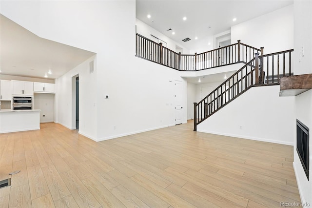 unfurnished living room with recessed lighting, stairway, visible vents, and light wood-type flooring