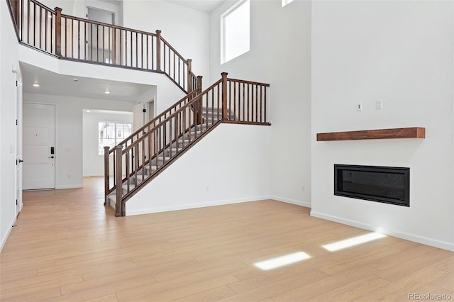 unfurnished living room with stairway, baseboards, and wood finished floors
