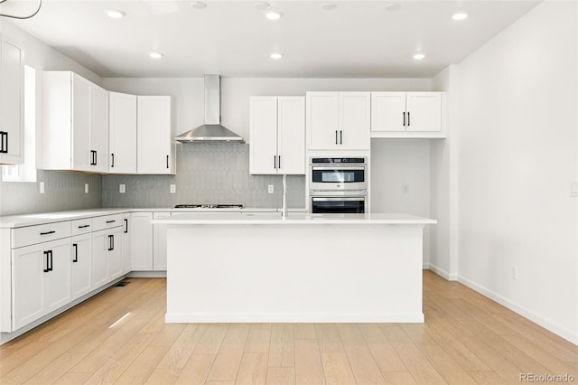 kitchen featuring light countertops, tasteful backsplash, and wall chimney range hood