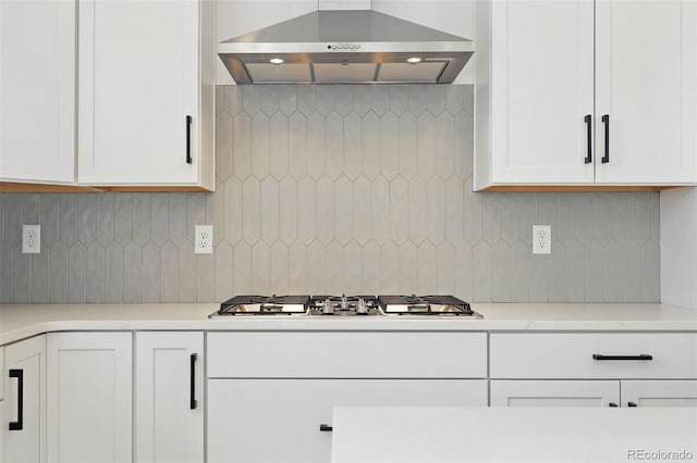 kitchen with stainless steel gas stovetop, light countertops, extractor fan, tasteful backsplash, and white cabinetry
