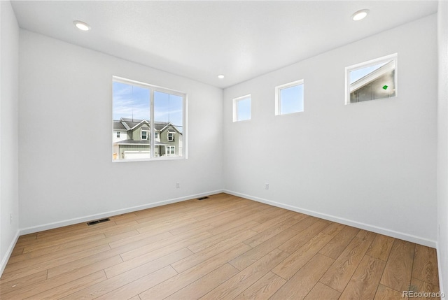 unfurnished room featuring light wood finished floors, baseboards, and visible vents