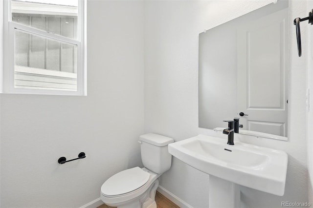 bathroom featuring toilet, a sink, and baseboards