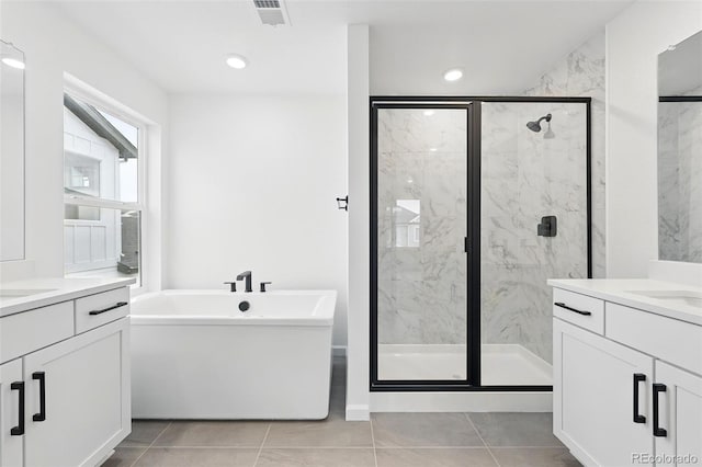 full bathroom with a marble finish shower, two vanities, visible vents, a freestanding tub, and tile patterned flooring