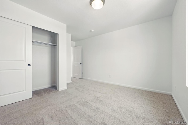 unfurnished bedroom with baseboards, carpet floors, and a closet