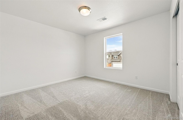 carpeted empty room featuring visible vents and baseboards