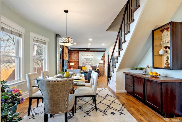 dining space with recessed lighting, stairway, brick wall, light wood finished floors, and baseboards