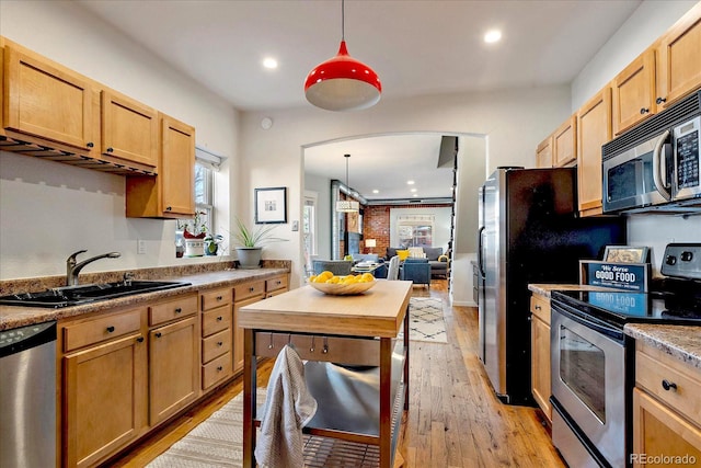 kitchen with light wood-style flooring, pendant lighting, appliances with stainless steel finishes, and a sink