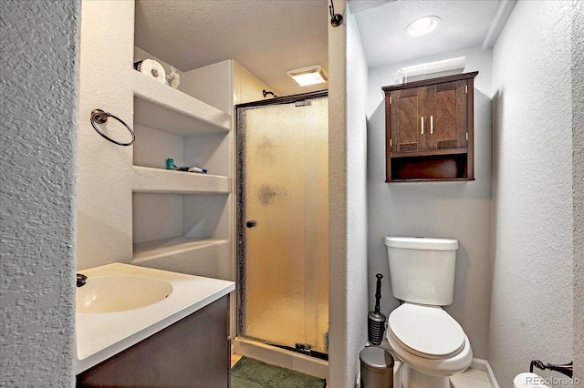 bathroom featuring a shower stall, toilet, a textured wall, and a sink