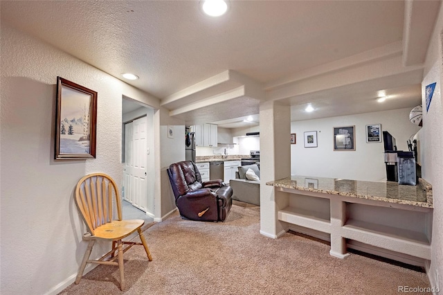 living area featuring recessed lighting, carpet, baseboards, and a textured wall