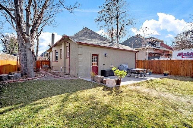 rear view of property featuring a patio, a fenced backyard, stucco siding, a chimney, and a lawn