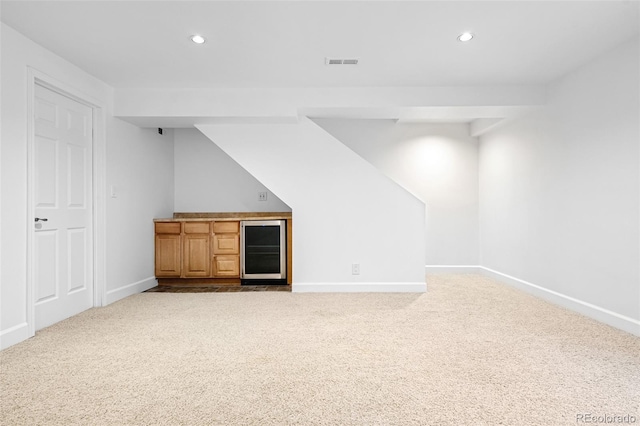 finished below grade area with a bar, carpet floors, baseboards, beverage cooler, and recessed lighting