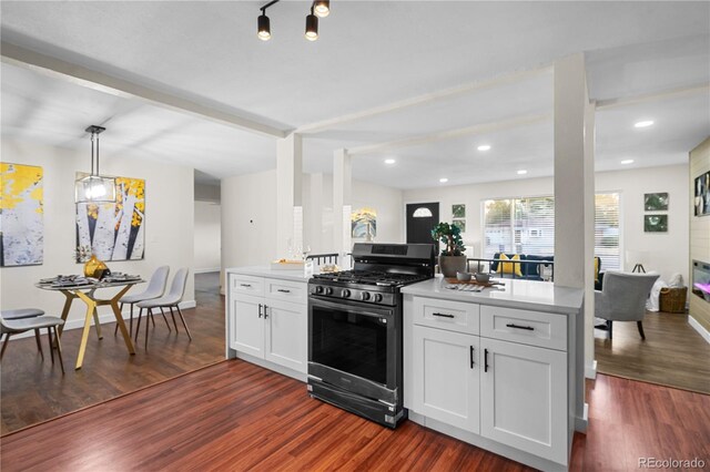 kitchen with kitchen peninsula, white cabinetry, dark hardwood / wood-style floors, and gas range oven