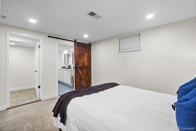 carpeted bedroom with a barn door and ensuite bath