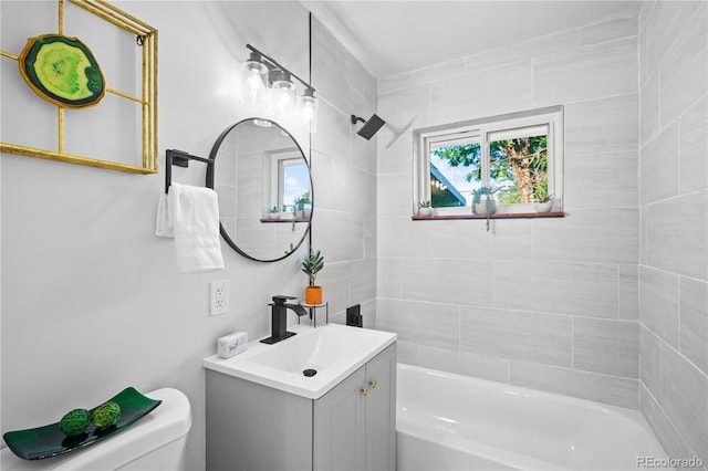 full bathroom featuring tiled shower / bath, vanity, and toilet