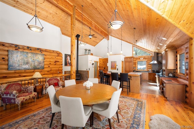 dining area featuring light wood-style flooring, log walls, wood ceiling, and high vaulted ceiling