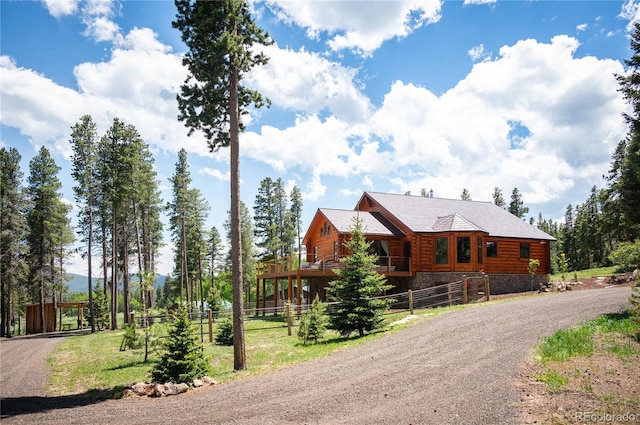 log home with stone siding, dirt driveway, and fence