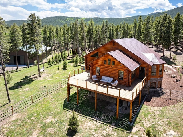 back of property with a forest view, fence, log exterior, an outdoor hangout area, and stone siding