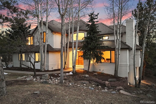 view of front of home featuring brick siding and a chimney