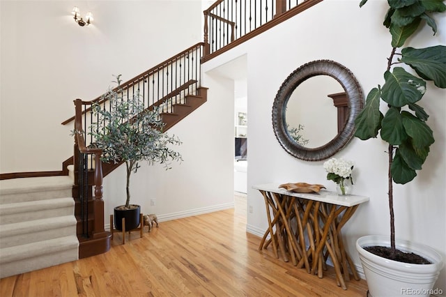 stairway featuring a high ceiling, baseboards, and wood finished floors