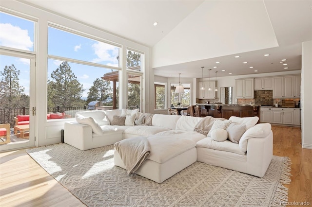 living room with high vaulted ceiling, light wood-type flooring, and recessed lighting