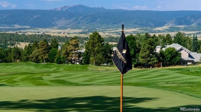 view of property's community featuring a lawn, golf course view, and a mountain view