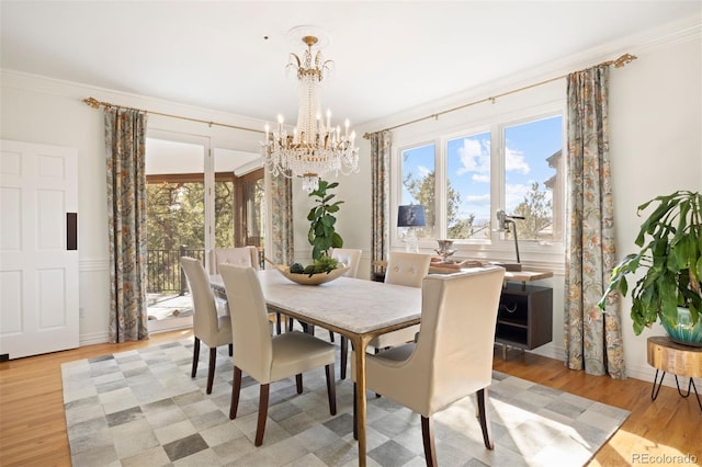 dining space with a chandelier, a healthy amount of sunlight, light wood-type flooring, and crown molding