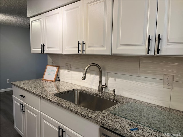 kitchen featuring light stone countertops, sink, decorative backsplash, and white cabinets